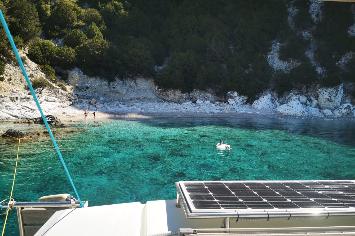 Turquoise water and white rocks seen from a catamaran in the Ionian