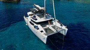 Aerial view of a catamaran at anchor in a turquoise bay in Greece